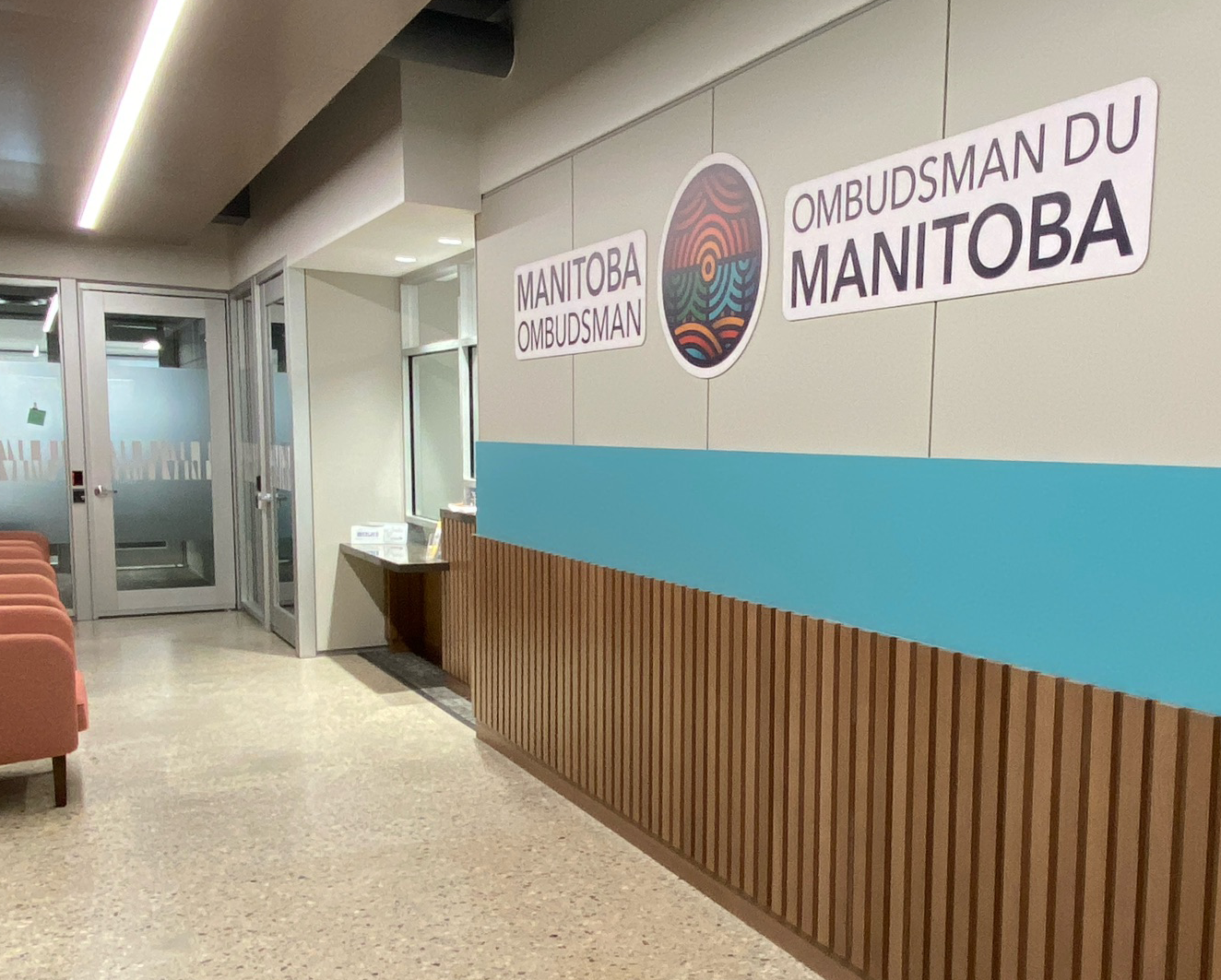 The lobby of the Manitoba Ombudsman’s Winnipeg office featuring a wall sign with the logo and a reception desk.